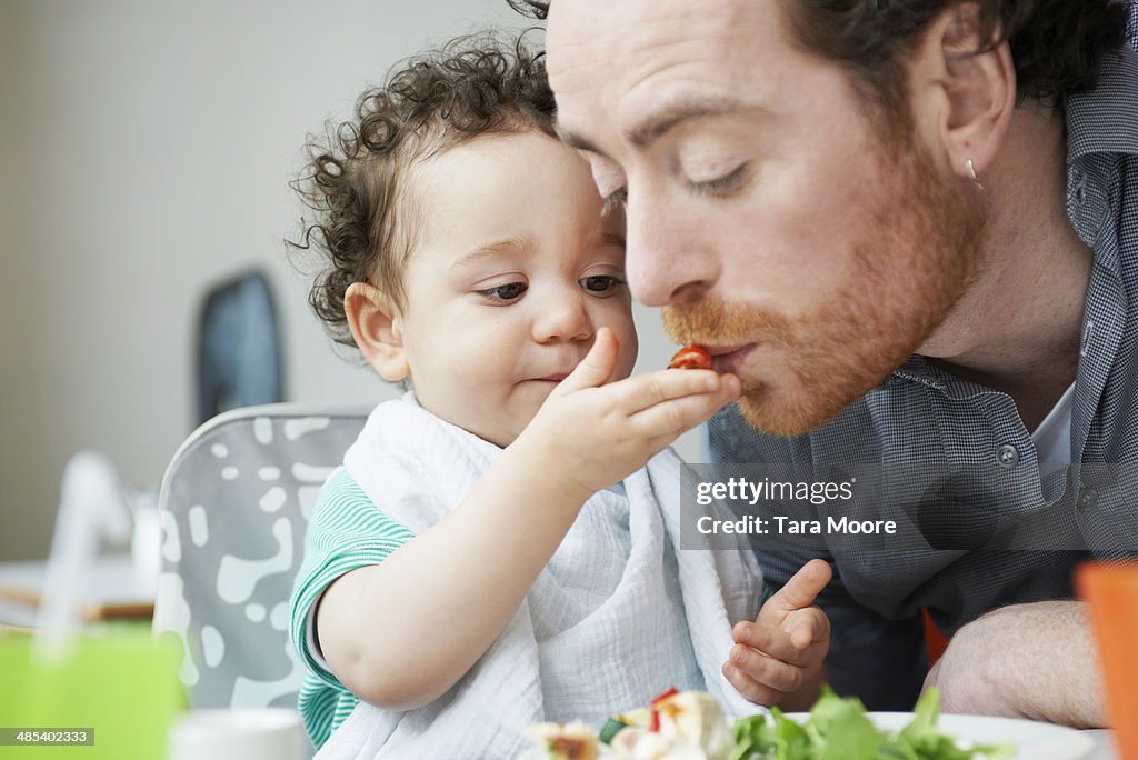 Young child feeding father