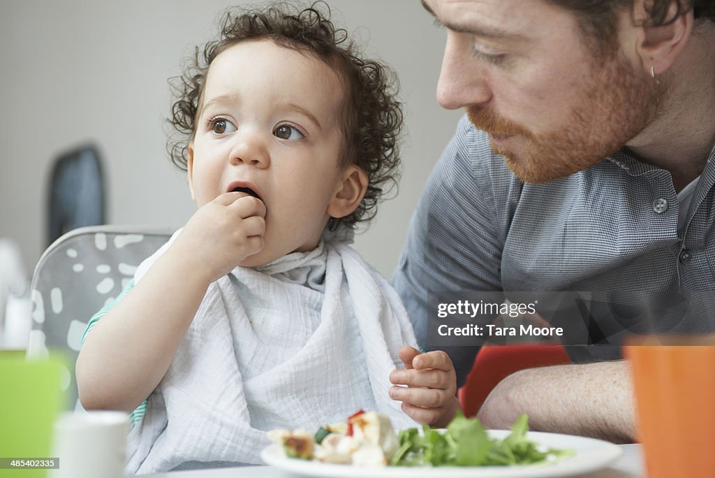 Young child eating lunch with father