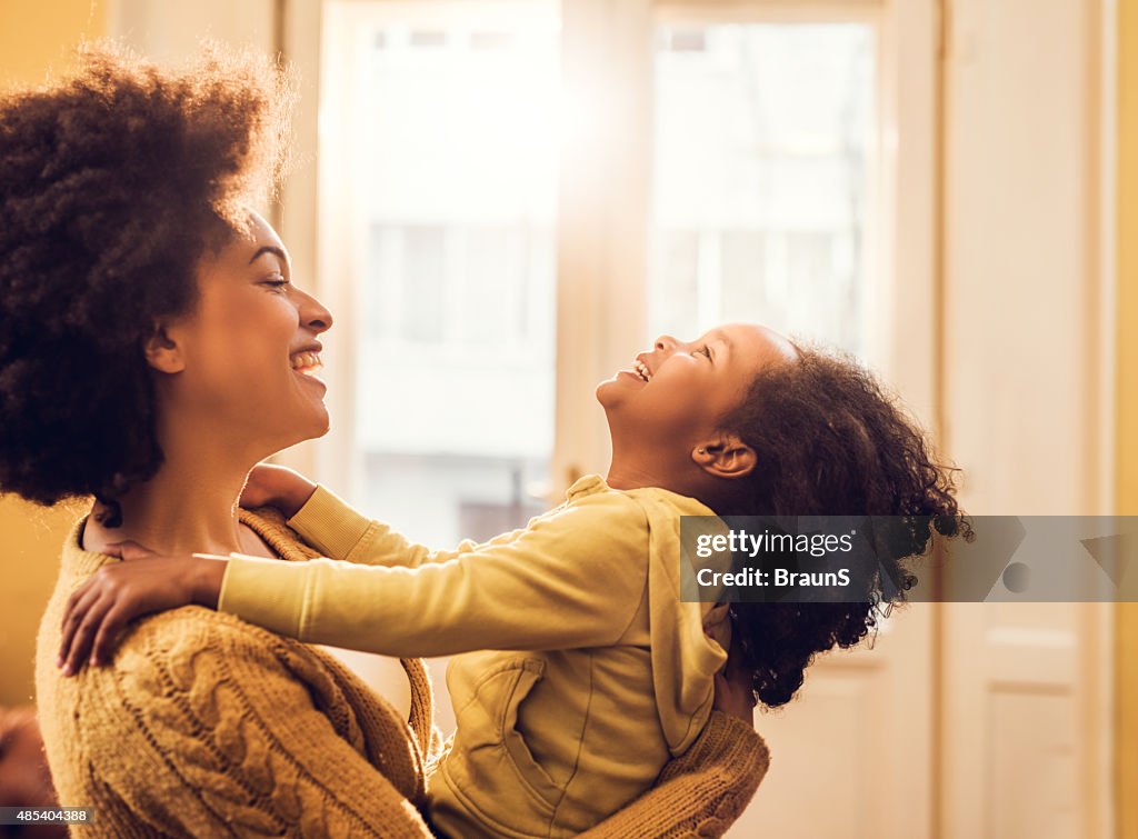 Playful African American mother and daughter having fun at home.