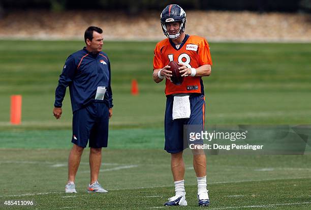 Quarterbacl Petyon Manning prepares to deliver a pass as head coach Gary Kubiak looks on during a joint training session with the San Francisco 49ers...