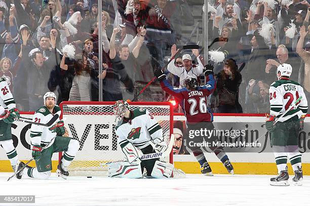 Paul Stastny of the Colorado Avalanche scores the game winning goal in overtime as members of the Minnesota Wild react in Game One of the First Round...