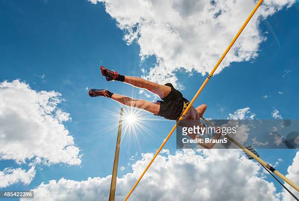 esecuzione maschio atleta salto in alto contro il cielo. - pole foto e immagini stock