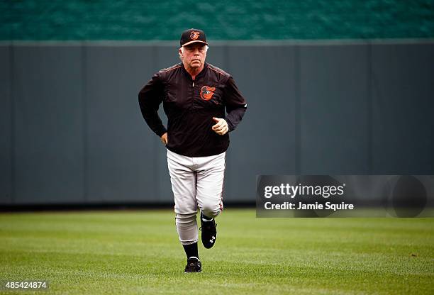 Manager Buck Showalter of the Baltimore Orioles jogs back to the dugout after checking on Adam Jones after Jones hit the wall while trying to catch a...