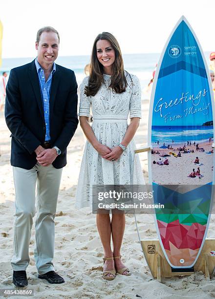 Catherine, Duchess of Cambridgeand Prince William, Duke of Cambridge pose with a surfboard they were given as they attend a lifesaving event on Manly...