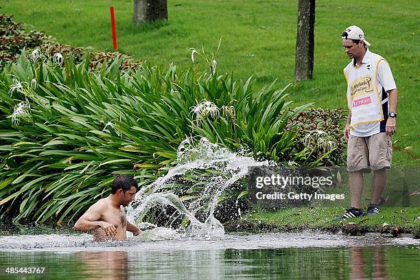 Spain's Pablo Larrazabal jumps into a water hazard in an attempt to avoid attacking hornets during round two of the 2014 Maybank Malaysian Open at...