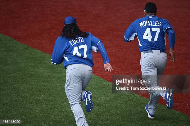 Johnny Cueto of the Kansas City Royals warms up with Franklin Morales while wearing the same number on their jerseys during batting practice before...