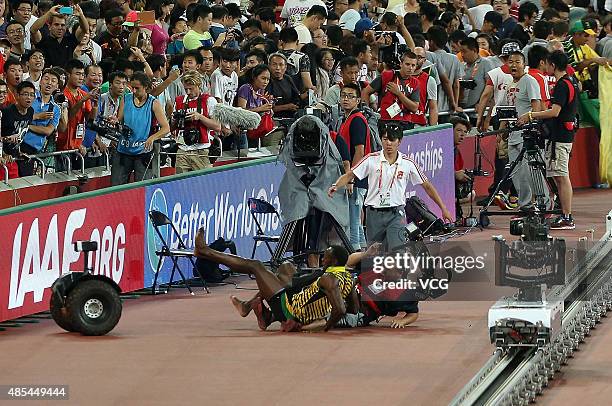 Usain Bolt of Jamaica collides with a worker as he celebrates after winning gold in the Men's 200 metres final during day six of the 15th IAAF World...