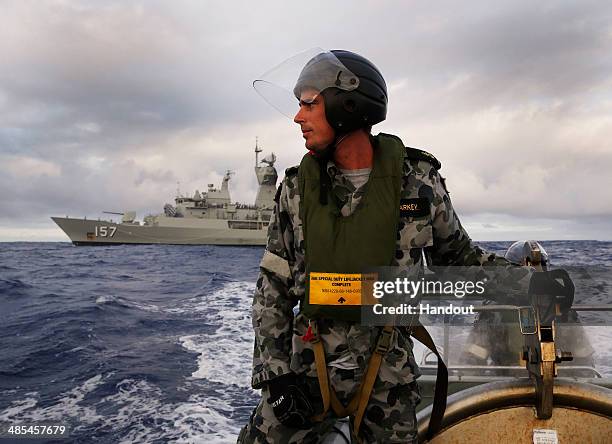 In this handout image provided by Commonwealth of Australia, Leading Seaman, Boatswain's Mate, William Sharkey searches for debris on a rigid hull...