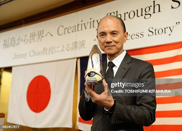 Malaysian designer Jimmy Choo holds his one-off set of shoes using materials of Japan's Fukushima area during his lecture "Creativity Thugh Skills"...