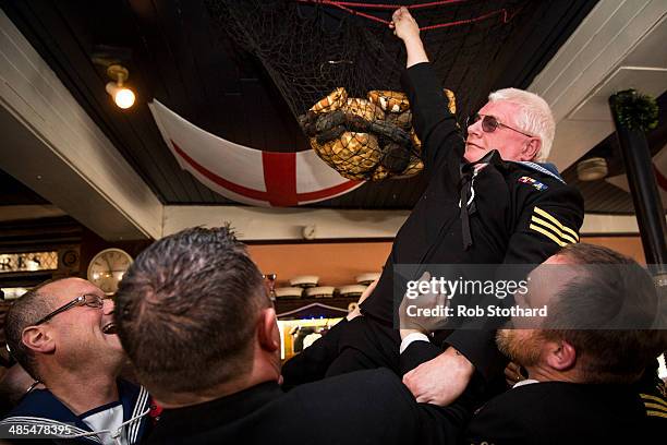 Royal Navel reservist from HMS President places a hot cross bun in a net above the bar of the Widow's Son pub in Bromley-by-Bow on April 18, 2014 in...