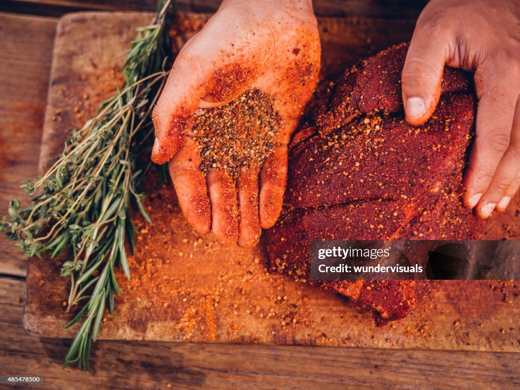 Hand showing spicy seasoning with a piece of raw pork