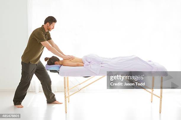 therapist working on patient at massage table - banc de massage photos et images de collection