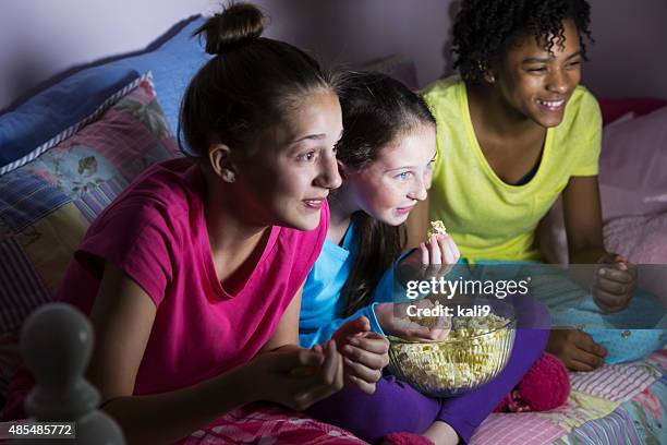 preteen mädchen im sleepover vor dem fernseher und essen popcorn - girls sleepover stock-fotos und bilder