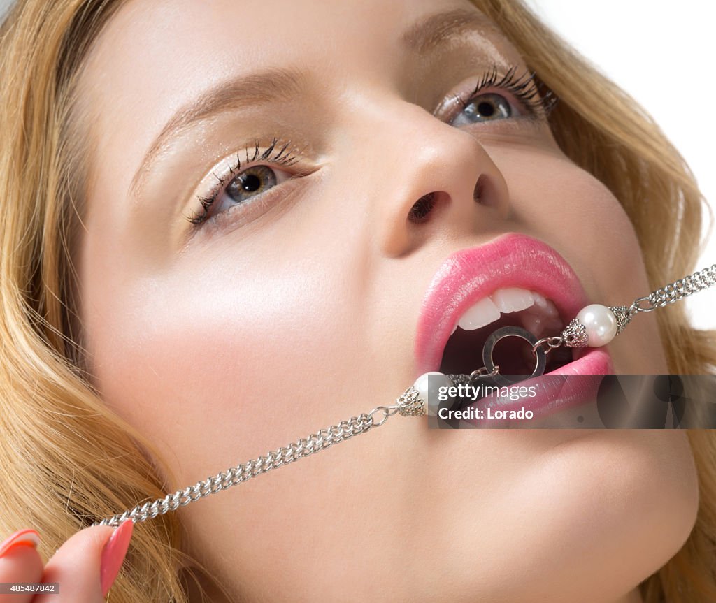 Gros plan de femme mordant collier de perles