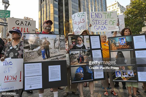 Rally attendees hold a set of photographic informational signs at the Columbus Circle concluding event. Demonstrators rallied at the American Museum...