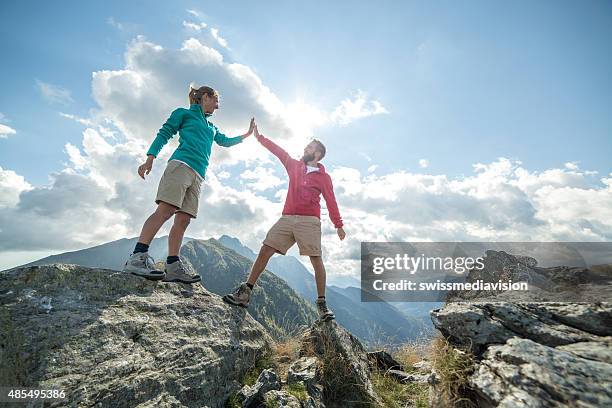 couple of hikers reaching the mountain top celebrating - man woman top view stockfoto's en -beelden