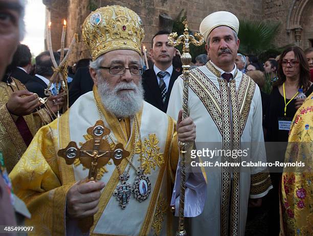 Cypriot Christian Orthodox preist and a Cypriot- Turkish Muslim relgious leader walk during a Good Friday procession, at the Ayios Georgios Exorinos...