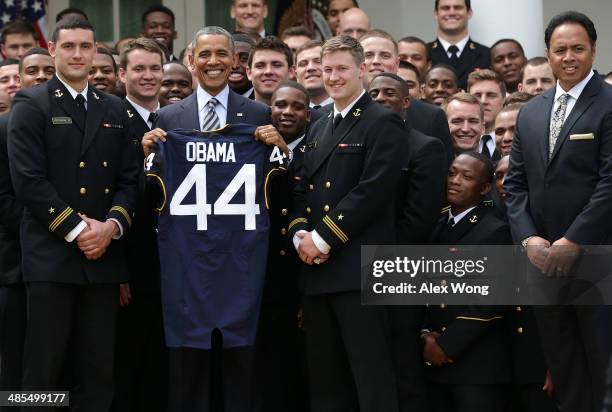 President Barack Obama holds a gift jersey he was presented as he poses during a presentation ceremony of the Commander-in-Chief's Trophy with...