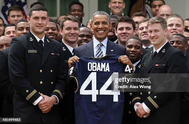 President Barack Obama holds a gift jersey he was presented as he poses during a presentation ceremony of the Commander-in-Chief's Trophy with...