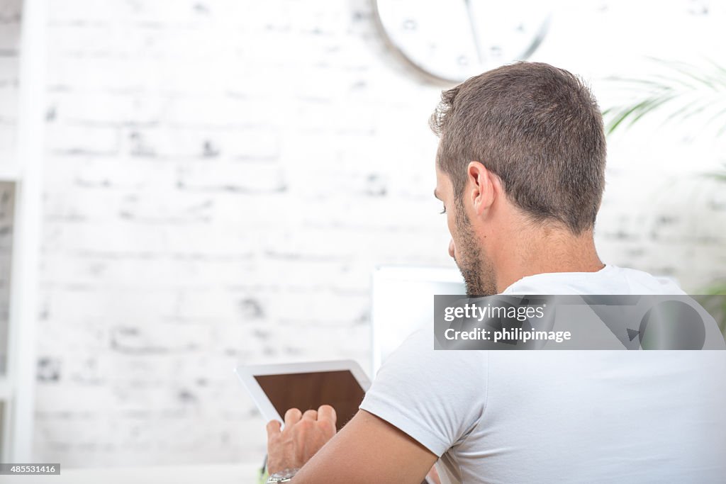 Young man from the back, looking at tablet