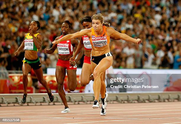 Dafne Schippers of the Netherlands crosses the finish line to win gold in the Women's 200 metres final ahead of second placed Elaine Thompson of...