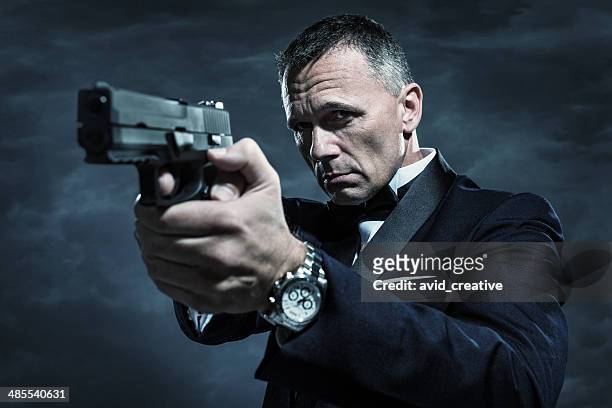 spy in tuxedo aiming gun - rich fury stock pictures, royalty-free photos & images