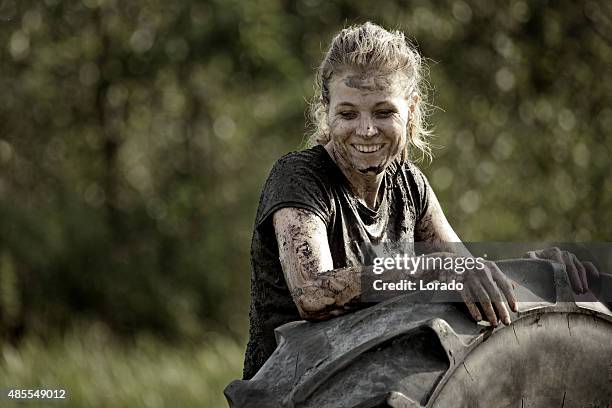 blond covered in mud pulls big tire during obstacle run - people covered in mud stock pictures, royalty-free photos & images