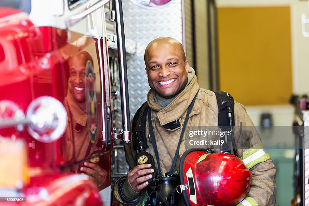 African American fire fighter standing next to truck