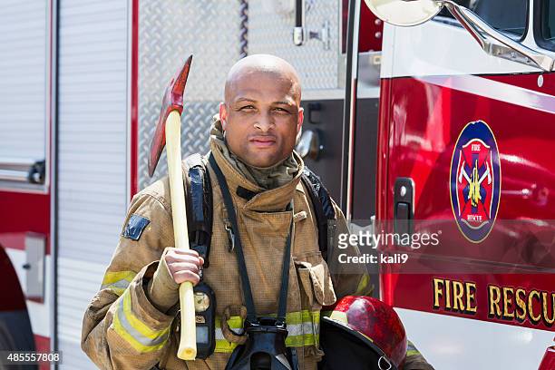 african american fire fighter carrying axe - fireman axe stock pictures, royalty-free photos & images