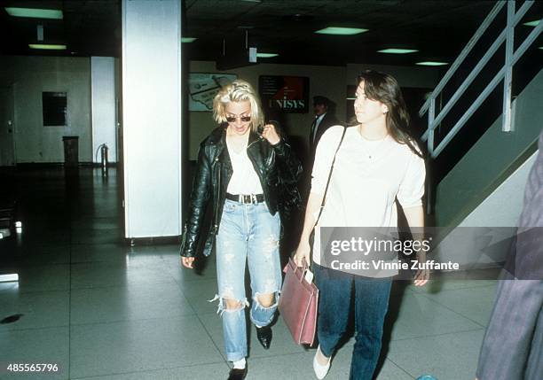 Singer Madonna walks with her assistant Melissa Crowe at the JFK airport wearing waist high blue jeans and a leather jacket circa 1988 in New York,...