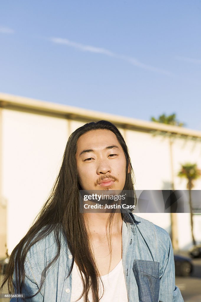 Portrait of a long haired man in a city scene
