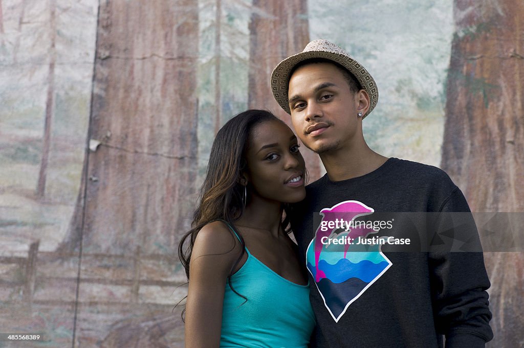 Couple holding each other in front of a mural