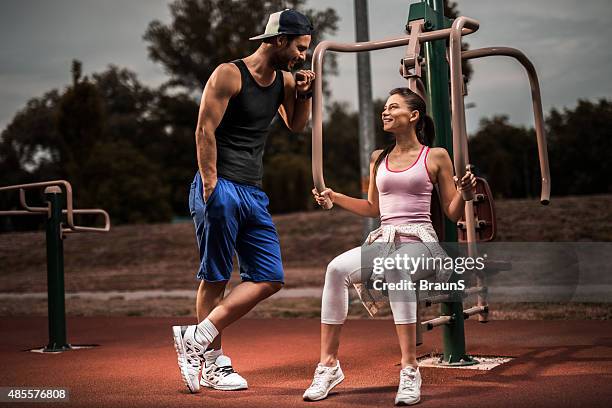 joven pareja sonriente mientras se comunican en el gimnasio al aire libre. - intimate couple in gym fotografías e imágenes de stock