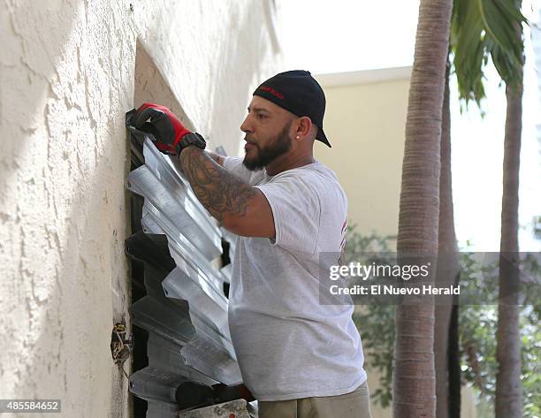 Employee from Joe's Stone Crab, Manny Cortes, installing shuttles in preparation for Tropical Storm Erika on Friday, August 28 in Miami Beach.