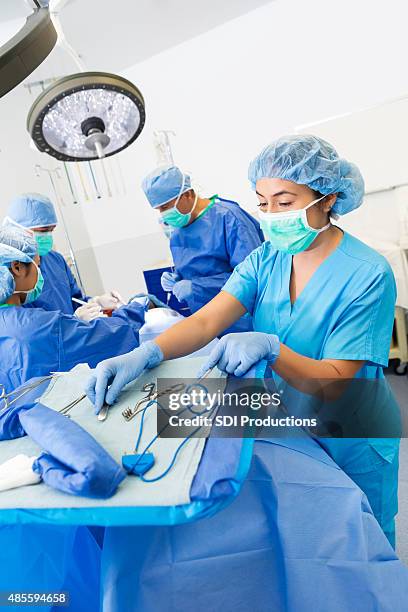 surgical technician prepping instruments while assisting doctors with surgery - surgical tray stock pictures, royalty-free photos & images