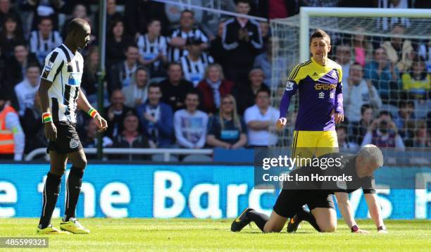 Referee Chris Foy struggles to his feet after the official was hit in the face by the ball during the Barclays Premier League match between Newcastle...