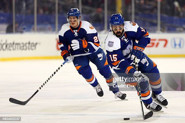 Cal Clutterbuck of the New York Islanders controls the puck against the New York Rangers during the 2014 Coors Light NHL Stadium Series at Yankee...