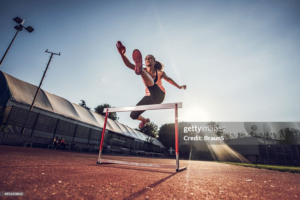 Low angle view of female athlete hurdling on sports race.