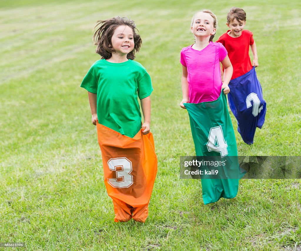 Three happy children in potato sack race