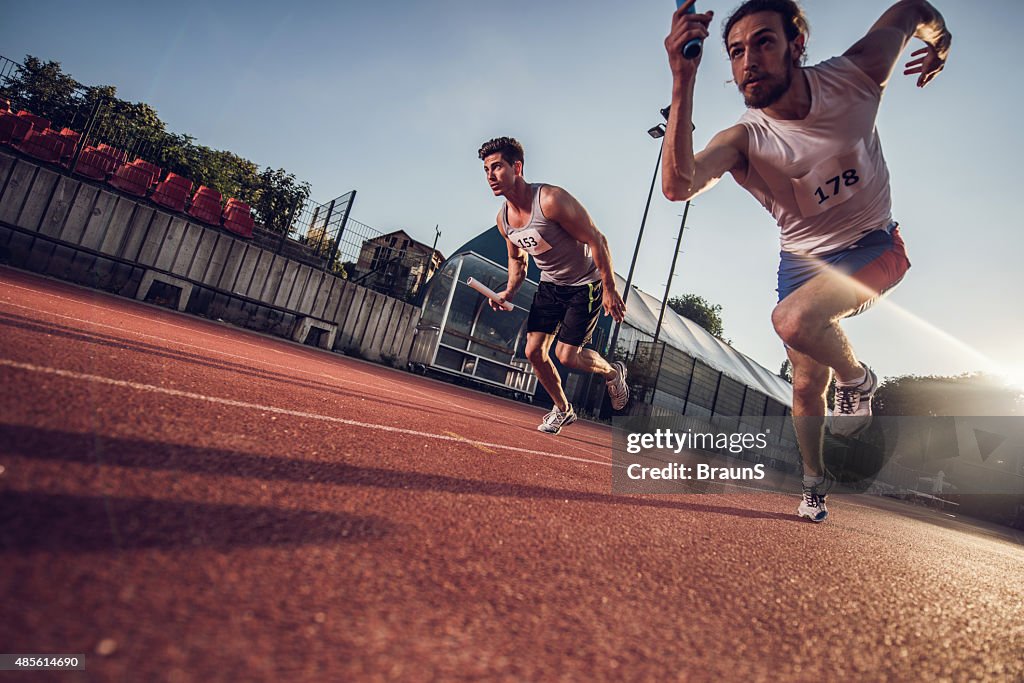 Tiefer Blickwinkel von Athleten auf einem Staffellauf wechselt.