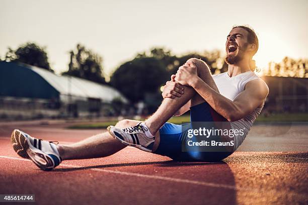 feriti maschio atleta urlare nel dolore al tramonto. - sports pain foto e immagini stock