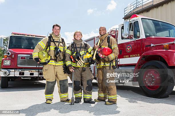 firefighters in protective gear with fire rescue trucks - fireman axe stock pictures, royalty-free photos & images