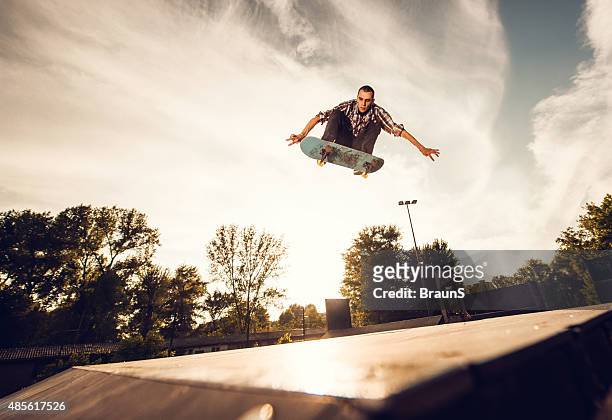 niedrigen winkel ansicht eines jungen mannes skateboarding bei sonnenuntergang. - x games stock-fotos und bilder