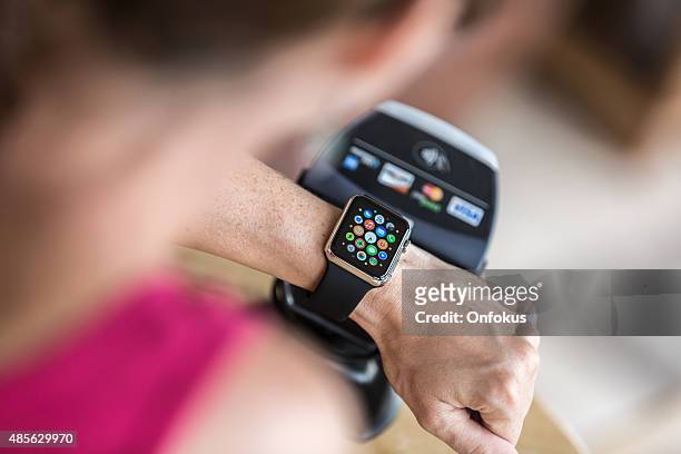 woman paying using apple watch and electronic reader - apple inc stockfoto's en -beelden