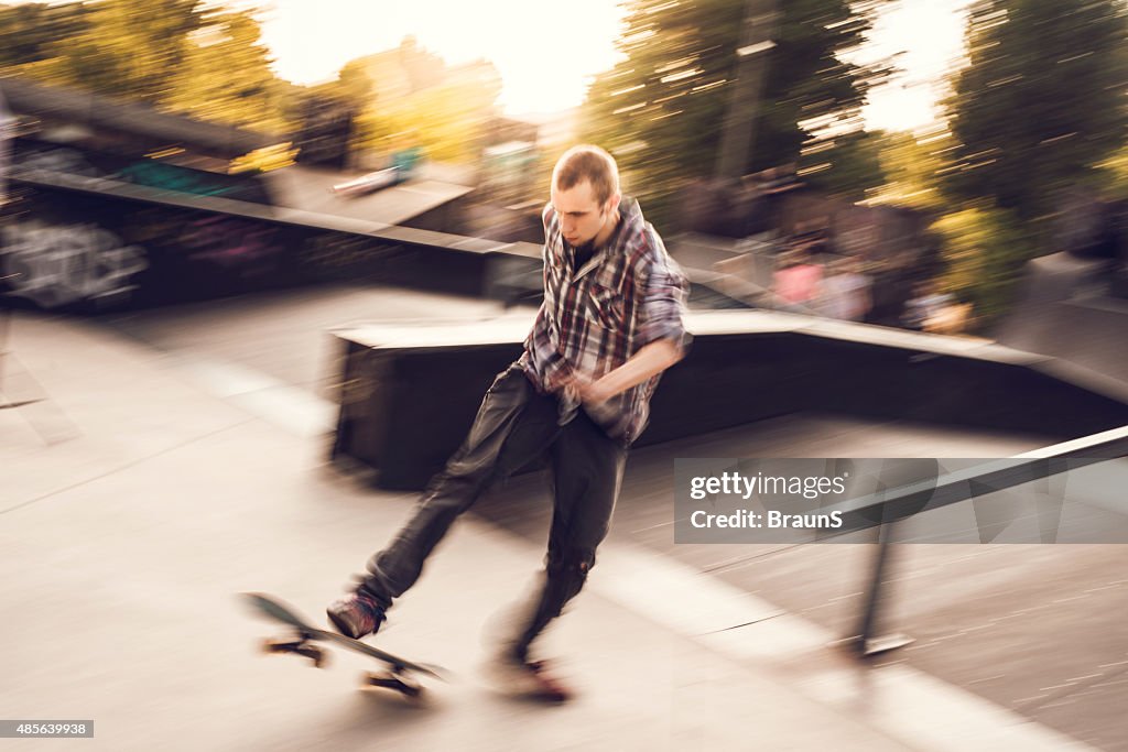 Young male skateboarder in blurred motion at the park.