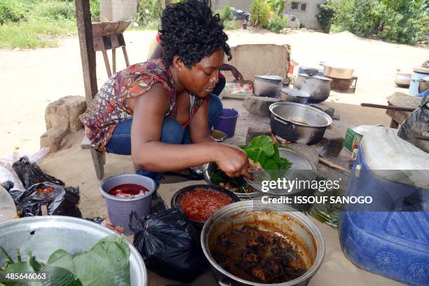 Woman prepares food at a "maquis," a small African restaurant, in Kobakro, outside Abidjan, which now serves various types of meat instead of...