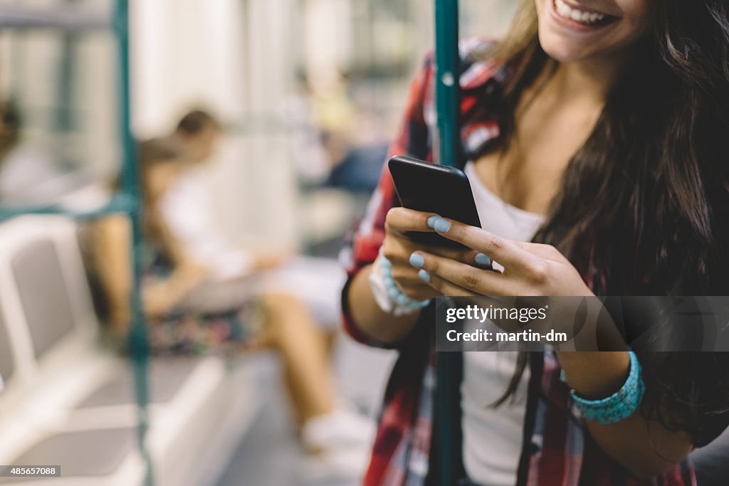 Teenage girl using phone in the subway train