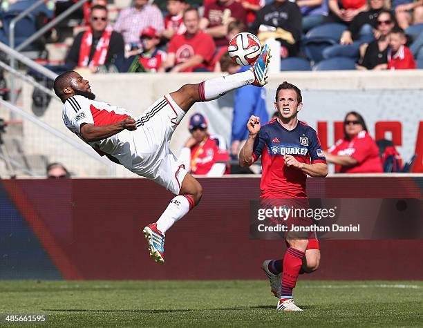 Andrew Farrell of the New England Revolution passes the ball with a bicycle kick next to Harry Shipp of the Chicago Fire during an MLS match at...