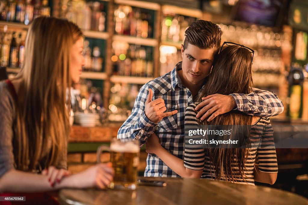 Unfaithful young man making call gesture in a cafe.