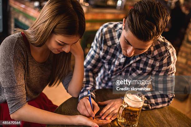 young man writing his phone number on woman's hand. - telephone number stock pictures, royalty-free photos & images